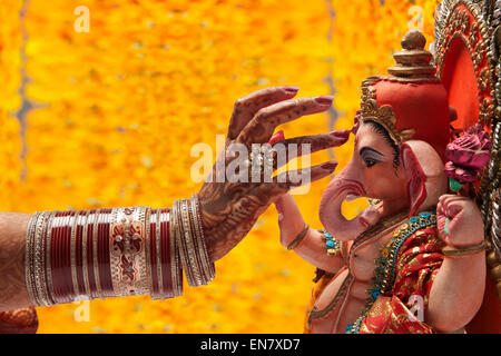 Close-up di una mano spose applicando tilak a ganesh idolo Foto Stock