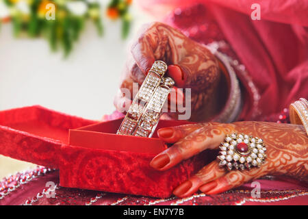 Close-up di spose ponendo le mani schiave in bangle box Foto Stock