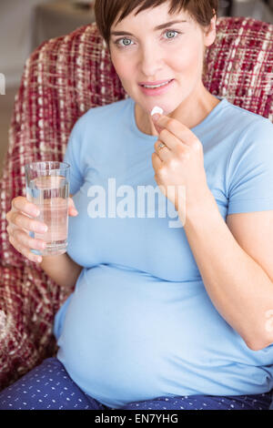 Donna incinta di prendere una compressa di vitamina Foto Stock