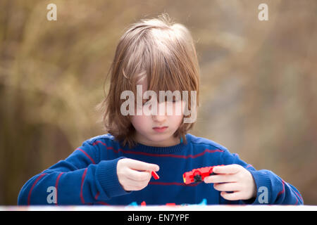 Ragazzo mettendo insieme il suo assemblaggio giocattoli all'aperto Foto Stock