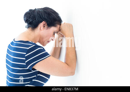 Triste donna appoggiata contro il muro Foto Stock