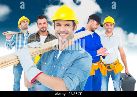 Immagine composita di felice falegname che trasportano tavole di legno Foto Stock