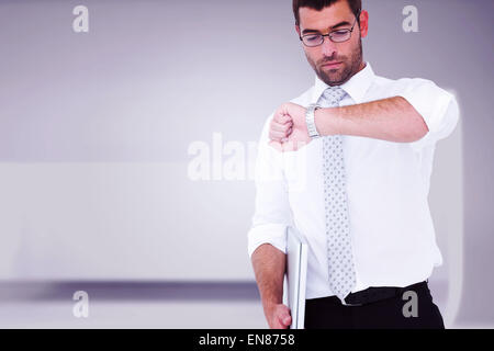 Immagine composita di grave imprenditore tenendo portatile il tempo di controllo Foto Stock