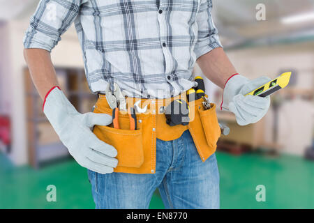 Immagine composita del tecnico mantenendo la livella su sfondo bianco Foto Stock