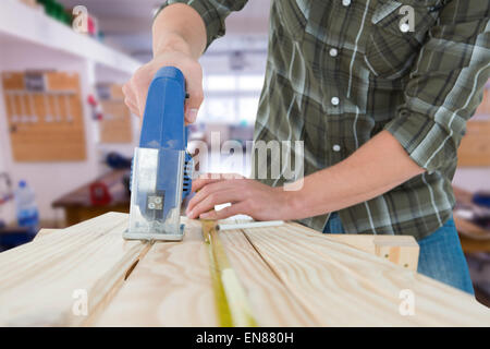 Immagine composita di carpenter il taglio di tavolato in legno con sega elettrica Foto Stock