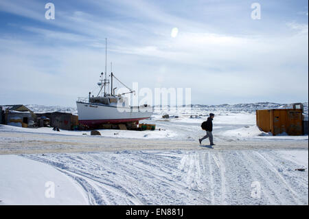 Un uomo cammina lungo una coperta di neve road accanto a una baia congelati come Stati Uniti Il segretario di Stato John Kerry visite Iqaluit, Canada, appena al di sotto del Circolo Polare Artico, il 24 aprile 2015, per le riunioni del Consiglio artico, la cui presidenza gli Stati Uniti assumeranno i prossimi due anni. Foto Stock