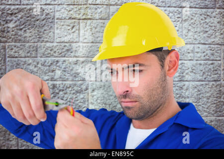 Immagine composita di elettricista indossare elmetto mentre il filo di taglio Foto Stock