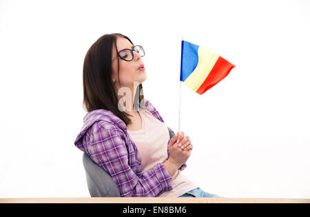 Giovane donna seduta al tavolo e soffiando sulla bandiera francese Foto Stock