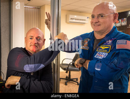 Ritirato la NASA Astronaut Mark Kelly, sinistra, pompe di pugno il suo gemello fratello, astronauta della NASA Scott Kelly attraverso il vetro come Scott Kelly e il compagno di equipaggio si accoppia, cosmonauti russo Gennady Padalka e Mikhail Kornienko di l'agenzia Spaziale Federale Russa Roscosmos () partecipano a una conferenza stampa mentre in quarantena Giovedì, 26 marzo 2015, presso il cosmonauta Hotel di Baikonur in Kazakhstan. Mark Kelly, che ha volato quattro missioni dello Space Shuttle e comandò l'ultimo volo della navetta spaziale Endeavour, parteciperà in studi biomedici sul terreno mentre il suo gemello è a bordo il labora orbitante Foto Stock