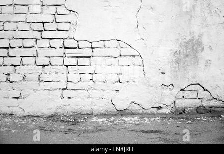 Abstract urban cortile interiore con il bianco danneggiato un muro di mattoni e asfalto Foto Stock