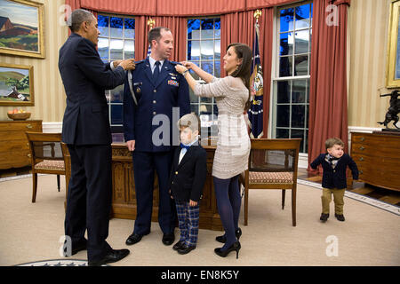 Il presidente Barack Obama partecipa a una cerimonia di promozione per militari Aide grandi Matthew 'Matt' Newell, USAF, promozione di lui per il grado di tenente colonnello, all Ufficio Ovale, Dicembre 5, 2014. Anche prendendo parte alla cerimonia sono Newell's moglie Tiffany Newell, e figli Brody, 4, e Rowan, 2. Foto Stock