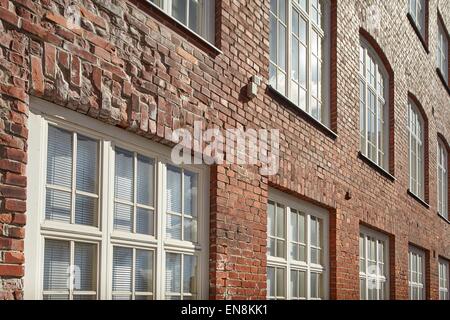 Muro di mattoni e finestre di un vecchio edificio sul soleggiato. Foto Stock