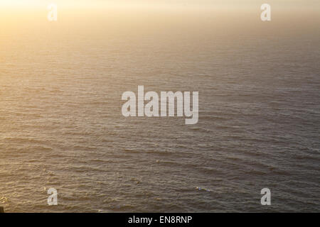 Fumoso calda luce del sole attraverso un instabile, blu scuro oceano. Foto Stock