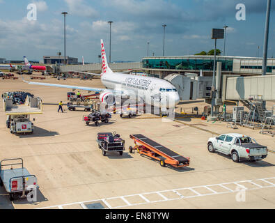 Bagaglio aereo carico di gestori di bagagli e merci su Virgin Australia aerei. Foto Stock