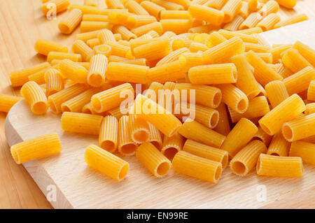 Un mucchio di penne non cotte pasta su una cucina tavolo in legno Foto Stock