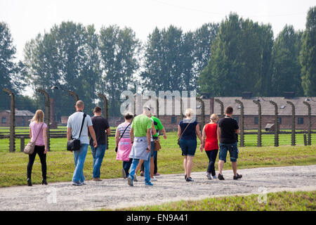 I turisti a piedi passato del filo spinato e blocchi al Campo di Concentramento di Auschwitz-Birkenau, Auschwitz, Polonia Foto Stock