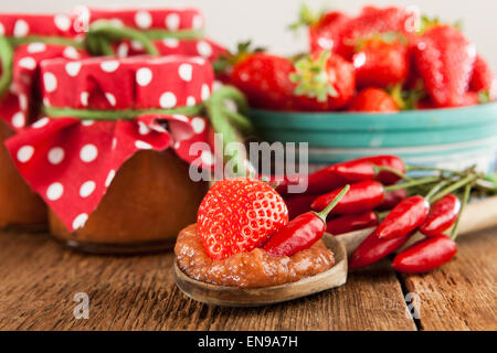 Fragole e peperoncino marmellata su una tavola in legno rustico Foto Stock