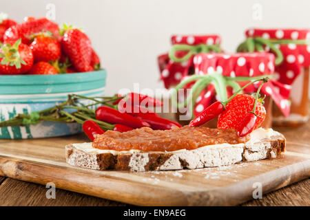 Uno snack su un tavolo rustico con peperoncino e confettura di fragole Foto Stock
