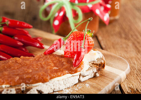 Uno snack su un tavolo rustico con peperoncino e confettura di fragole Foto Stock