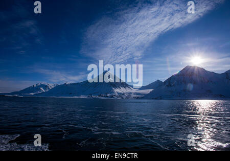 Spitsbergen, Norvegia. 09Apr, 2015. Il sole splende sopra le montagne coperte di neve vicino al Kings Bay stazione di ricerca in Ny-Alesund su Spitsbergen, Norvegia, 09 aprile 2015. Foto: Jens Büttner/dpa/Alamy Live News Foto Stock