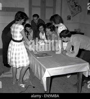 Degli anni Cinquanta, gruppo di adolescenti che si riuniscono intorno al tavolo per ascoltare la musica da una bobina all'altra macchina. Foto Stock