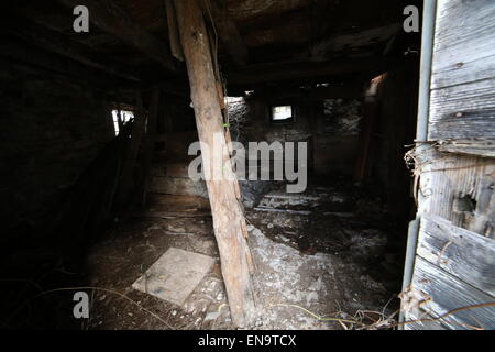 Casa abbandonata in rovina con pericolo di crollo e una vecchia scala di legno Foto Stock