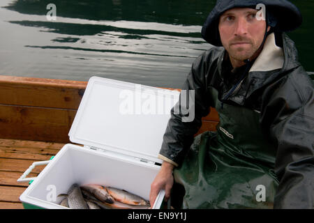 Pescatore con la sua cattura di Saibling su una barca a Grundlsee, Stiria, Austria Foto Stock