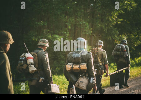 Unidentified re-enactors vestiti come i soldati tedeschi durante il mese di marzo attraverso la foresta di estate Foto Stock