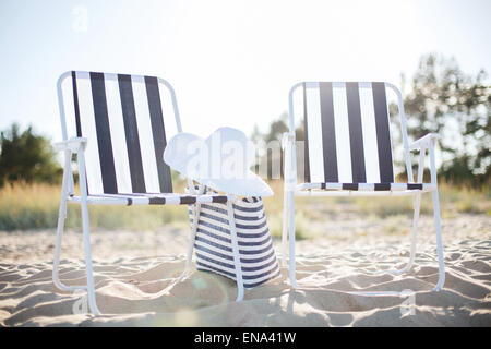 Spiaggia di due saloni con borsa da spiaggia e cappello bianco Foto Stock