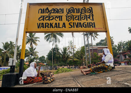I passeggeri in attesa su piattaforma sottostante Varkala stazione ferroviaria segno Foto Stock