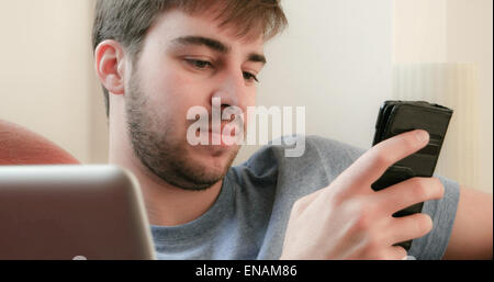 Giovane uomo utilizzando un telefono cellulare e il computer portatile. Foto Stock