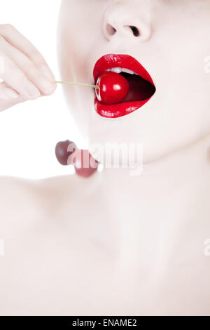 Concetto di donna bianco mangiare ciliegia. Chiudere la moda di ripresa. Ciliegia di colore rosso su una donna bianca la bocca. Riprese in studio Foto Stock