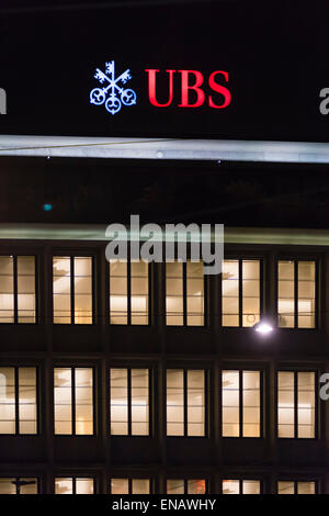 Il neon rosso logo di UBS Svizzera, la più grande banca, splende nella notte sulla parte superiore della sede a Zurigo. Foto Stock