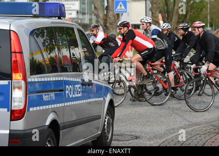 Eschborn, Germania. 01 Maggio, 2015. Un gruppo di ciclisti passa una macchina della polizia di Eschborn, Germania, 01 maggio 2015. Il Eschborn-Frankfurt City Loop bicycle race è stato annullato dopo le munizioni e le forniture della bomba sono stati trovati nell'appartamento di un paio in Oberursel. Ancora alcuni ciclisti hanno gareggiato sotto la protezione della polizia. Foto: Arne Dedert/dpa/Alamy Live News Foto Stock