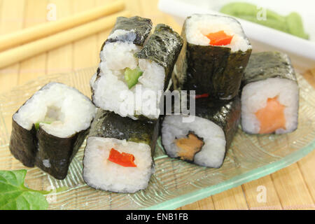 Un vaso di vetro con sushi e wasabi lascia Foto Stock