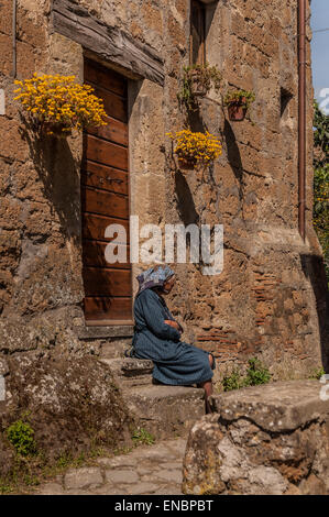Malinconici donna seduta sui gradini di Civita di Bagnoregio, Italia Foto Stock