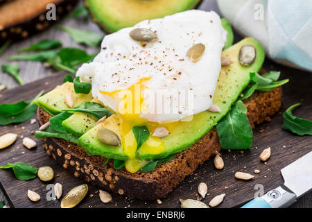 Sandwich di Avocado con rucola, semi e Uovo affogato Foto Stock