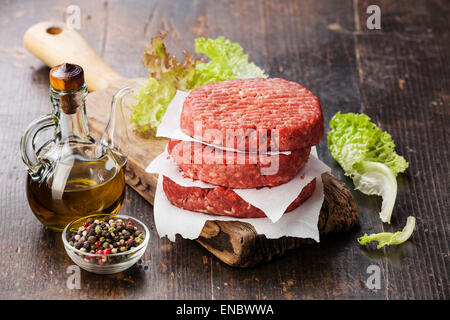 Materie di macinato di manzo hamburger di carne costolette di manzo e condimenti su scuro dello sfondo in legno Foto Stock