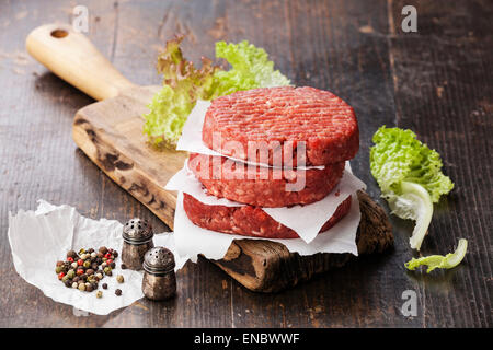 Materie di macinato di manzo hamburger di carne costolette di manzo e condimenti su scuro dello sfondo in legno Foto Stock
