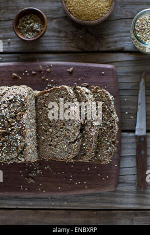 Pane appena sfornato, miglio e grano saraceno a fette di pane su un tagliere. Foto Stock