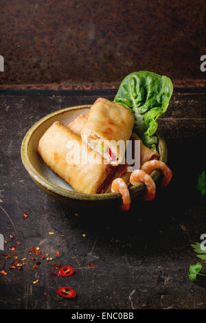 Fritti involtini primavera con verdure e gamberi, servito in tazza di ceramica su sfondo nero. Foto Stock