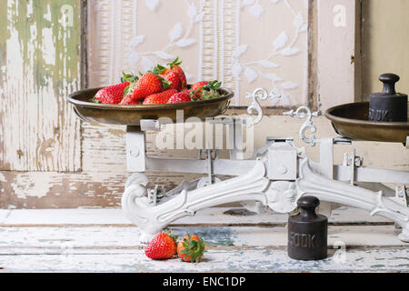 Pesi e scale vintage con fragole fresche su bianco tavolo in legno Foto Stock