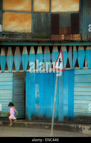 Una bambina esce da una porta su una strada di Pakse, Laos Foto Stock