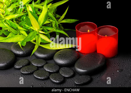 Spa concept di ramoscelli bambù con rugiada e candele rosse su zen pietre di basalto, primo piano Foto Stock