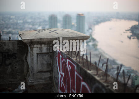 Vista verso il fiume Chao Phraya da un edificio abbandonato coperto di graffiti, Bangkok, Thailandia. Foto Stock