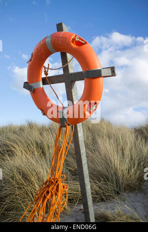 Anello Lifeboy situato in dune di sabbia vicino a una spiaggia costiera, England, Regno Unito Foto Stock