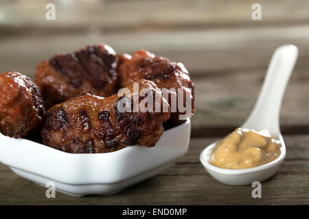 Cibo tradizionale polpettine di carne " ICI " su una tavola in legno rustico con mostarda Foto Stock