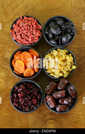 Un assortimento di frutta secca (uva passa, albicocche, fichi, prugne, goji, mirtilli rossi) in ciotole Foto Stock