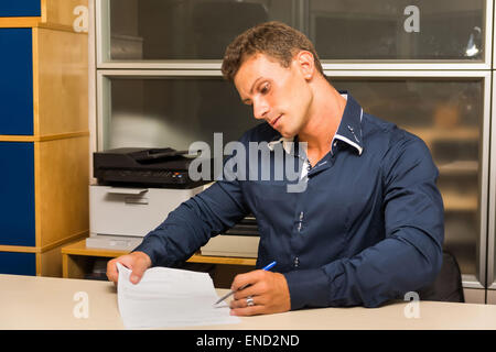 Giovane uomo facendo documenti all ufficio, mostrando un documento Foto Stock