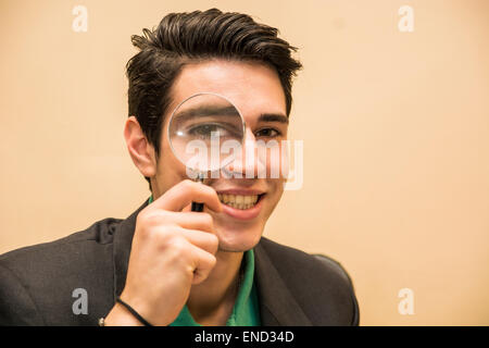 Bel giovane uomo con una lente di ingrandimento Foto Stock